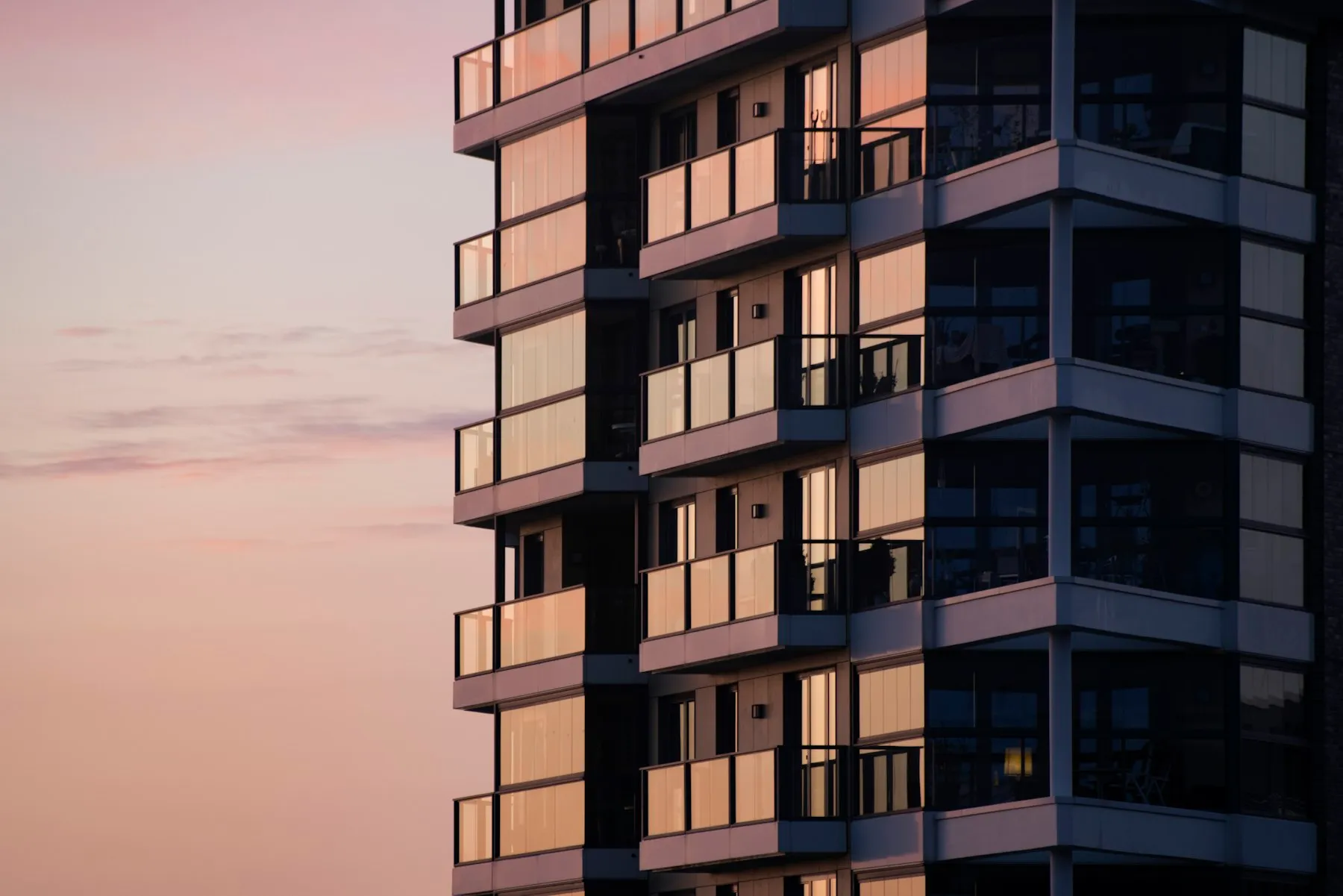 O prédio do Alto da Maré ao entardecer, com as varandas de vidro refletindo o céu rosado
